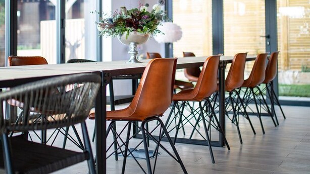 A modern dining area with a wooden ceiling, large windows, and a table with chairs.