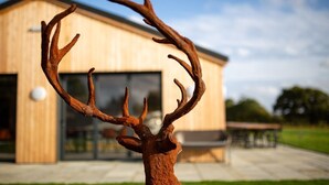 A rustic deer antler sculpture in front of a modern building with large windows and a patio area.