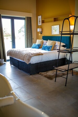 Un dormitorio con cama, una silla, una escalera y vistas al exterior.
