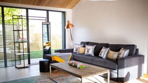 A modern living room with a grey sofa, a coffee table, and a large window with a view of a garden.