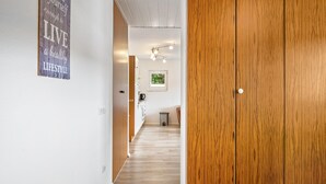 Ein Flur mit einer Holztür, einem Küchenbereich im Hintergrund und einem Wandplakat.