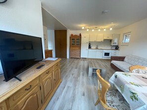 A living room with a TV, wooden furniture, a sofa, and a dining area with a table and chairs. - Apartment approx. 53 m² with Terrace (Niedereschach)