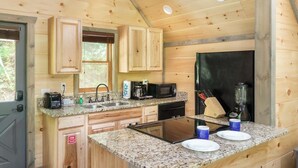 Cocina de cabaña de madera con encimeras de granito, un refrigerador, un lavamanos y armarios.