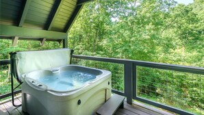 Un jacuzzi en una terraza de madera con vista a un bosque.