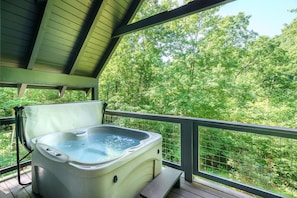 A hot tub on a wooden deck with a view of a forest. - Lil' Smoky Studio (Gatlinburg)