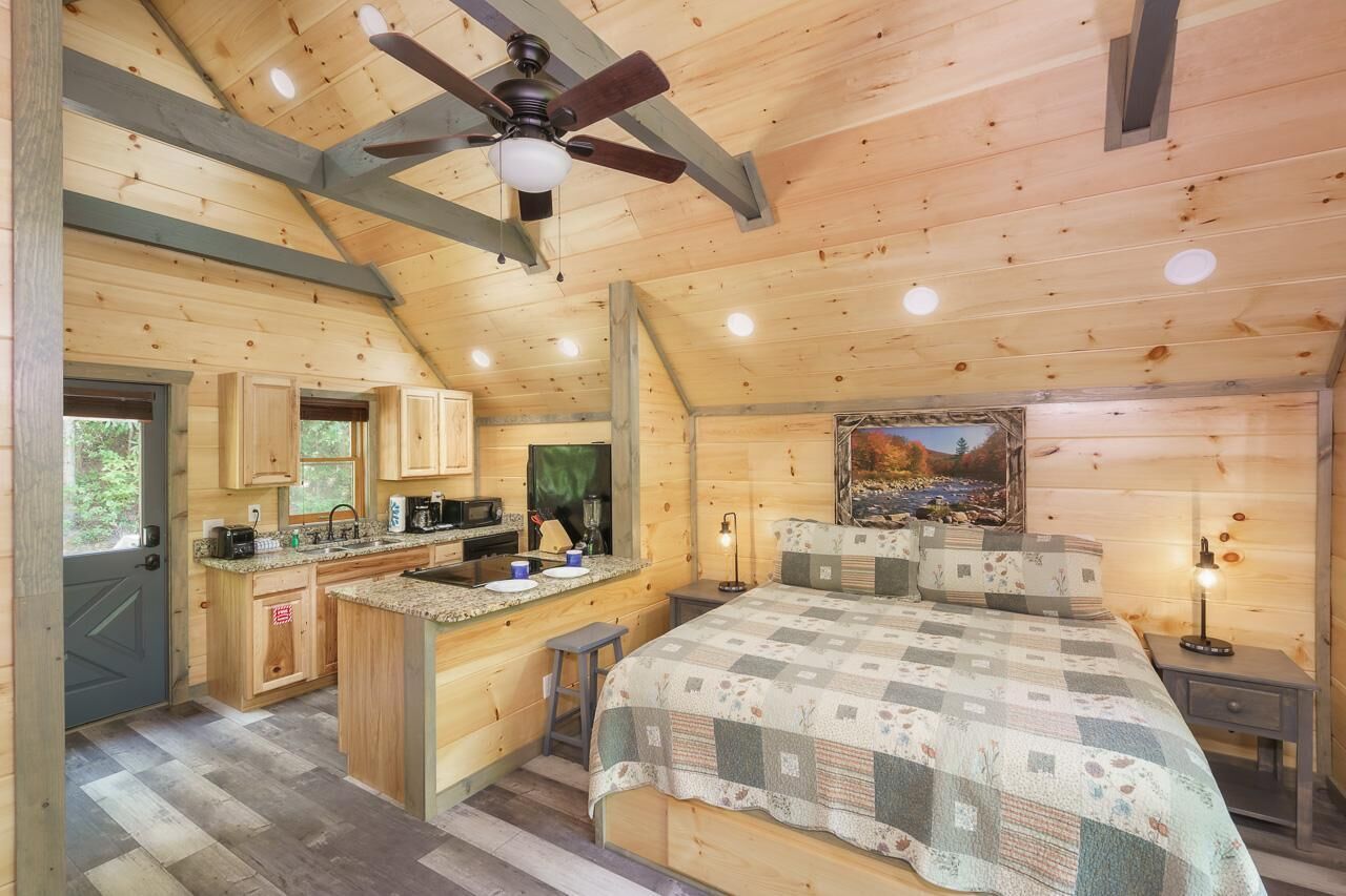 A cabin interior with a kitchen, a dining area, and a bedroom.