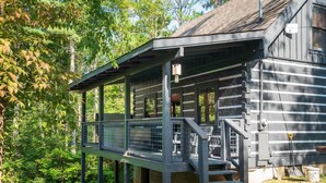 A wooden cabin with a covered porch and a fenced deck area. - Lakeside Rendezvous (Gatlinburg)