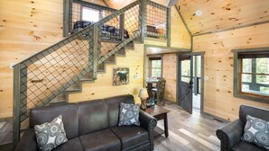 A wooden interior with a staircase, a sofa, and a table. - Lakeside Rendezvous (Gatlinburg)