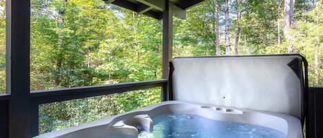 A hot tub with a view of a forested area.