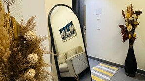 A hallway with a mirror, a sofa, and decorative plants. - OnlyStay Villa Vista Galaxy BlueSapphire (Noida)