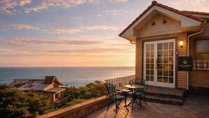 A wooden villa with a tiled roof overlooking the ocean, a patio with chairs, and a sign reading 'Villa Amoria Ocean View.' - Peaceful Ocean View Villa with Free Parking & Full Kitchen (Miyazaki)