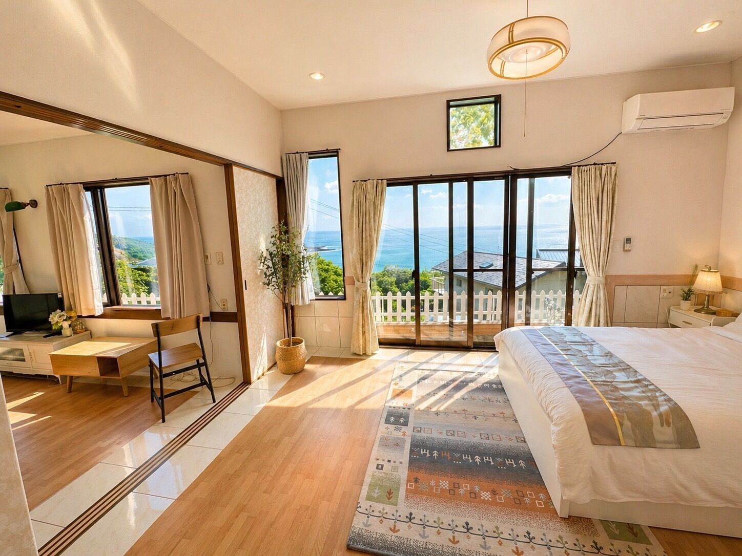 Habitación de hotel con una cama grande, un escritorio, una silla, una planta en maceta y vistas al mar.