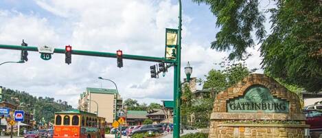Una intersección con un tranvía, un letrero de piedra que dice 'Gatlinburg' y un semáforo.