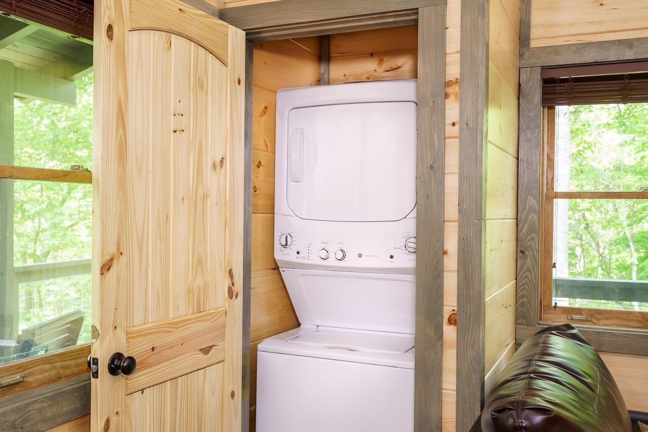 A compact room with a washing machine, wooden walls, and a window.