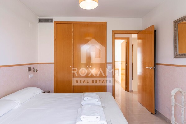 Ein Hotelzimmer mit einem Bett, einem Kleiderschrank, einem Spiegel und einer Tür zu einem weiteren Raum.