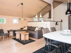 Un interior moderno con techo de madera, un sofá, una mesa de comedor e iluminación colgante.