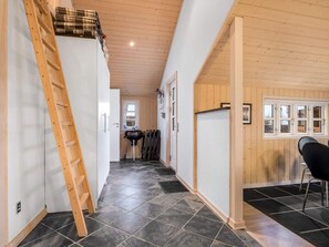 Un couloir étroit avec une échelle en bois, un barbecue et une chaise noire.