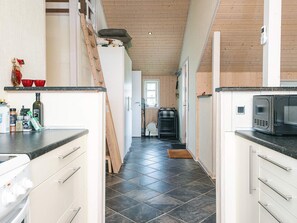 A narrow kitchen with a wooden ceiling, a microwave, and a stove.
