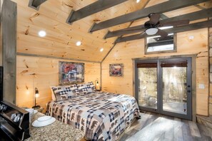 A cozy bedroom with a bed, ceiling fan, and a sliding glass door to the outside. - Serenity Studio (Gatlinburg)
