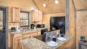 A compact kitchen with wooden cabinets, a microwave, a toaster, and a sink. - Solitude Studio (Gatlinburg)