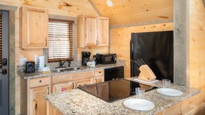 Una cucina compatta con mobili in legno, un frigorifero nero, un forno a microonde, un tostapane e un lavandino.