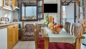 Una cucina con zona pranzo, mobili in legno, un divano e un tavolo con una ciotola di frutta.