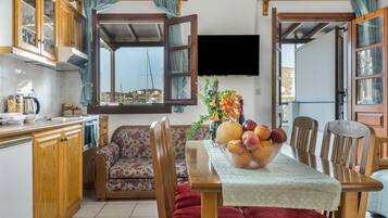 A kitchen with a dining area, wooden cabinets, a sofa, and a table with a fruit bowl.