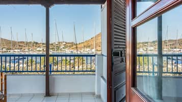 A balcony with a view of sailboats, a tiled floor, and a wooden door.