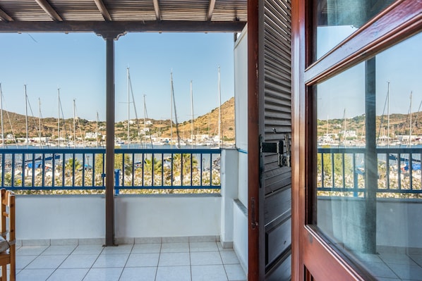 A balcony with a view of sailboats, a tiled floor, and a wooden door.