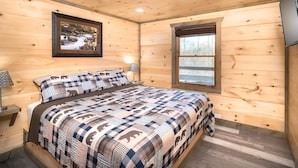 Una habitación con paneles de madera, una cama, un cuadro en la pared, una ventana y un televisor de pantalla plana.