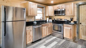 Una cocina moderna con armarios de madera, electrodomésticos de acero inoxidable y encimera negra.