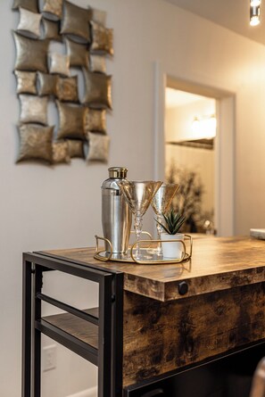 A wooden bar counter with a cocktail shaker, two martini glasses, and a small potted plant. - Breathe taking resort in the heart of the Lower Mission. (Kelowna)