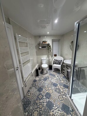 A bathroom with a patterned tile floor, a white toilet, a white sink, and a glass shower enclosure. - 2 Bed Cottage - Sleeps 4 - Parking - Wifi (Melrose)