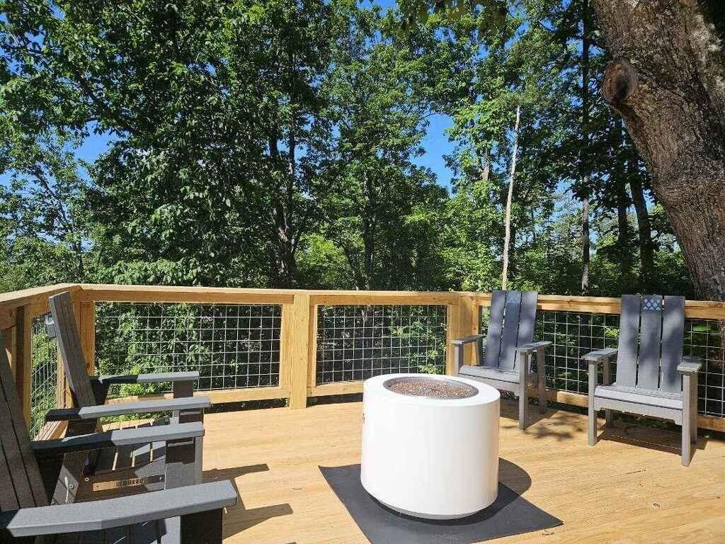 A deck with a fire pit, two chairs, and a wooden railing.