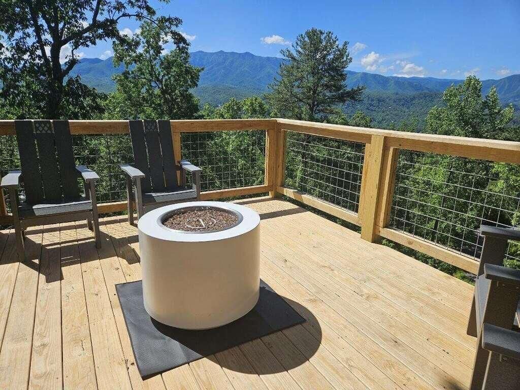 Une terrasse en bois avec un jardinière circulaire, des chaises et une vue sur les montagnes.