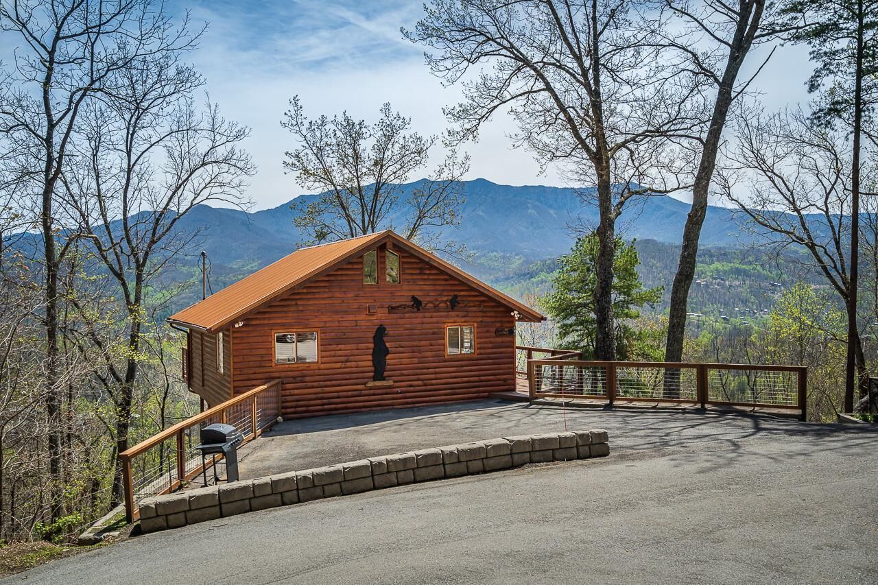 A wooden cabin with a balcony, surrounded by trees and mountains.