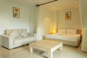 Ein modernes Hotelzimmer mit Sofa, Bett, Couchtisch und zwei Wandlampen.