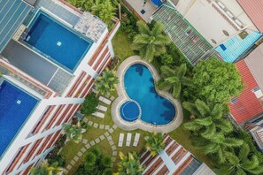 Ein Pool, umgeben von Palmen und ein Gebäude mit rotem Dach.