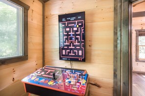 Ein Zimmer mit Flipperautomaten und einem Spielebildschirm an der Wand.