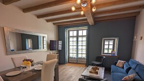 A living room with a dining area, a TV, and a large window. - Ideal for families, couples and relaxing holidays, swimming pool, quiet, authentic. (Julienne)