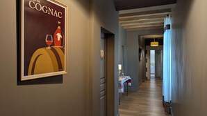 A hallway with a framed poster, a table with a lamp, and a wooden floor. - Ideal for families, couples and relaxing holidays, swimming pool, quiet, authentic. (Julienne)