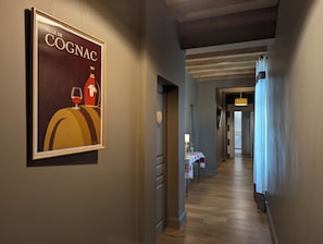 A hallway with a framed poster, a table with a lamp, and a wooden floor.