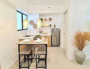 Una cocina moderna con una mesa de comedor para cuatro, un refrigerador y una planta en maceta.