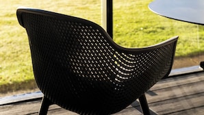 A wicker chair on a wooden deck with a view of a grassy field and trees in the background. - 55 Guthrie - Gleneagles Village (Gleneagles Village)