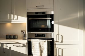 A kitchen with a built-in oven, microwave, and a hanging towel.