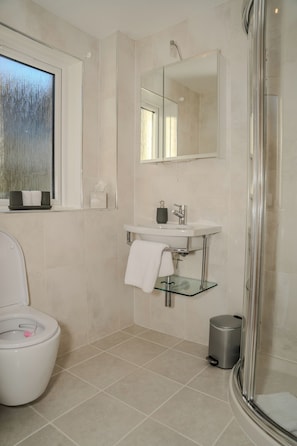A modern bathroom with a toilet, sink, mirror, and shower.