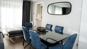 A modern dining area with a glass table, blue chairs, and a large mirror on the wall. - 55 Guthrie - Gleneagles Village (Gleneagles Village)