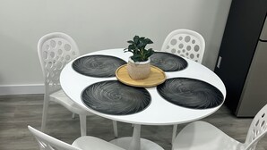 Une table ronde agrémentée d’un pot de fleurs, entourée de chaises blanches dotées d’ouvertures circulaires.
