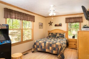 A bedroom with a bed, a ceiling fan, a window with a view, a desk with a computer, and a game console. - A Heavenly View (Sevierville)