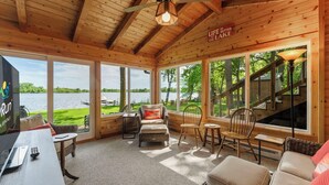 A cabin with a wooden interior, large windows, a TV, and a sign that says 'Life is better at the lake.' - Granite Lake Retreat w/ Private Dock (Annandale)